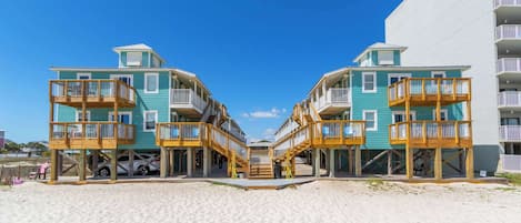 A beachfront hotel with multiple balconies, a sandy beach in front, and a clear blue sky.