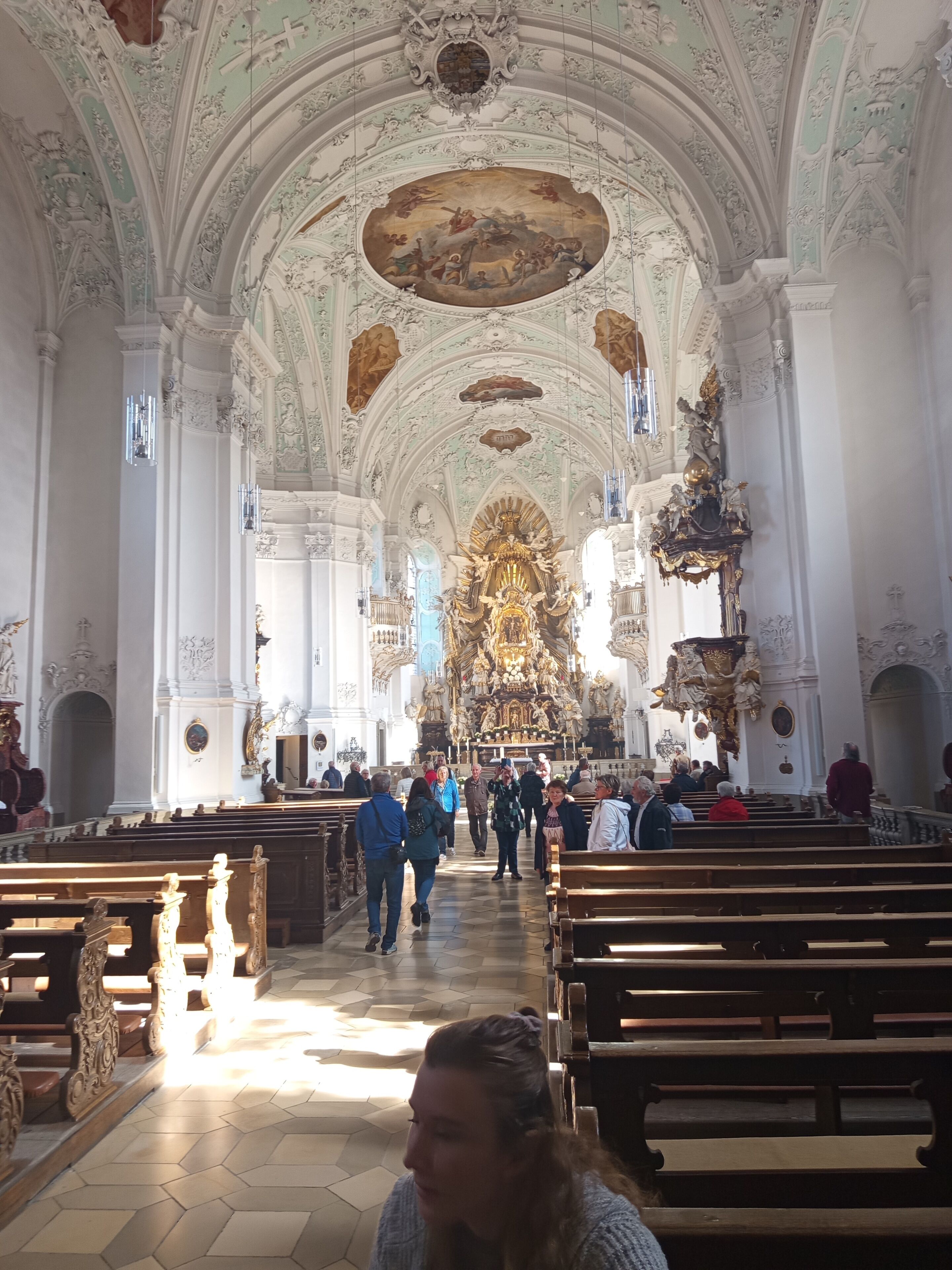 Interior con techos ornamentados, bancales y un altar central.