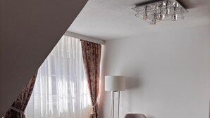 A modern hotel room with a large bed, a chair, a floor lamp, and a small table with a vase. - Fruntz Vacation Rental – A Family-Friendly Getaway in Franconian Switzerland 🏡🌳 (Gößweinstein)