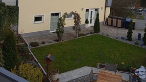 A two-story house with a balcony, a small garden, and a patio area with outdoor furniture. - Fruntz Vacation Rental – A Family-Friendly Getaway in Franconian Switzerland 🏡🌳 (Gößweinstein)