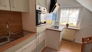 A compact kitchen with a built-in oven, a sink, and a window with a view. - Fruntz Vacation Rental – A Family-Friendly Getaway in Franconian Switzerland 🏡🌳 (Gößweinstein)
