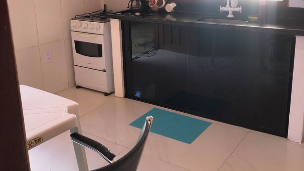A kitchen with a stove, oven, coffee maker, and a window. - House 150 meters from the beach. (Paraty)
