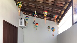 A room with a wooden ceiling, a bed with a floral bedspread, and multiple colorful hanging decorations. - House 150 meters from the beach. (Paraty)