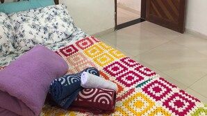 A bedroom with a bed, a colorful blanket, a wooden door, and a small picture on the wall. - House 150 meters from the beach. (Paraty)
