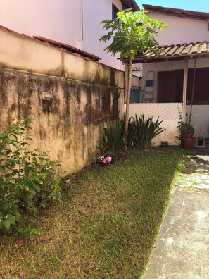 A concrete wall with a metal gate, a small tree, and potted plants. - House 150 meters from the beach. (Paraty)