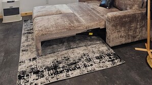 Una sala de estar con un sofá, un tapete, un cuadro y un ventilador de techo.