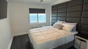 A bedroom with a bed, a window, a ceiling fan, and a nightstand. - Cozy 2-bedroom condo in quaint Virginia Beach with AC and gym (Virginia Beach)