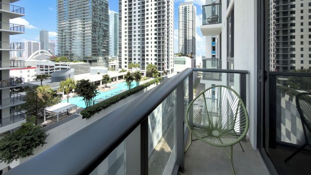 A balcony with a view of high-rise buildings, a swimming pool, and a chair. - C1611 - Modern Boho Retreat with Pool & City Views in Miami Downtown (Miami)
