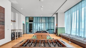 A modern indoor space with a pool table, foosball table, and seating area with large windows. - C1611 - Modern Boho Retreat with Pool & City Views in Miami Downtown (Miami)