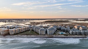 Une zone résidentielle côtière comprenant plusieurs immeubles d’appartements, une plage et une vaste étendue d’eau.