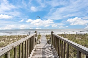 A wooden boardwalk leading to the beach with a clear sky and ocean in the background. - 'A Sunny Delight - 6BR - Oceanfront - Sleeps 15 (North Topsail Beach)