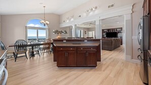A spacious kitchen with a large island, wooden cabinets, and a dining area with chairs. - 'A Sunny Delight - 6BR - Oceanfront - Sleeps 15 (North Topsail Beach)