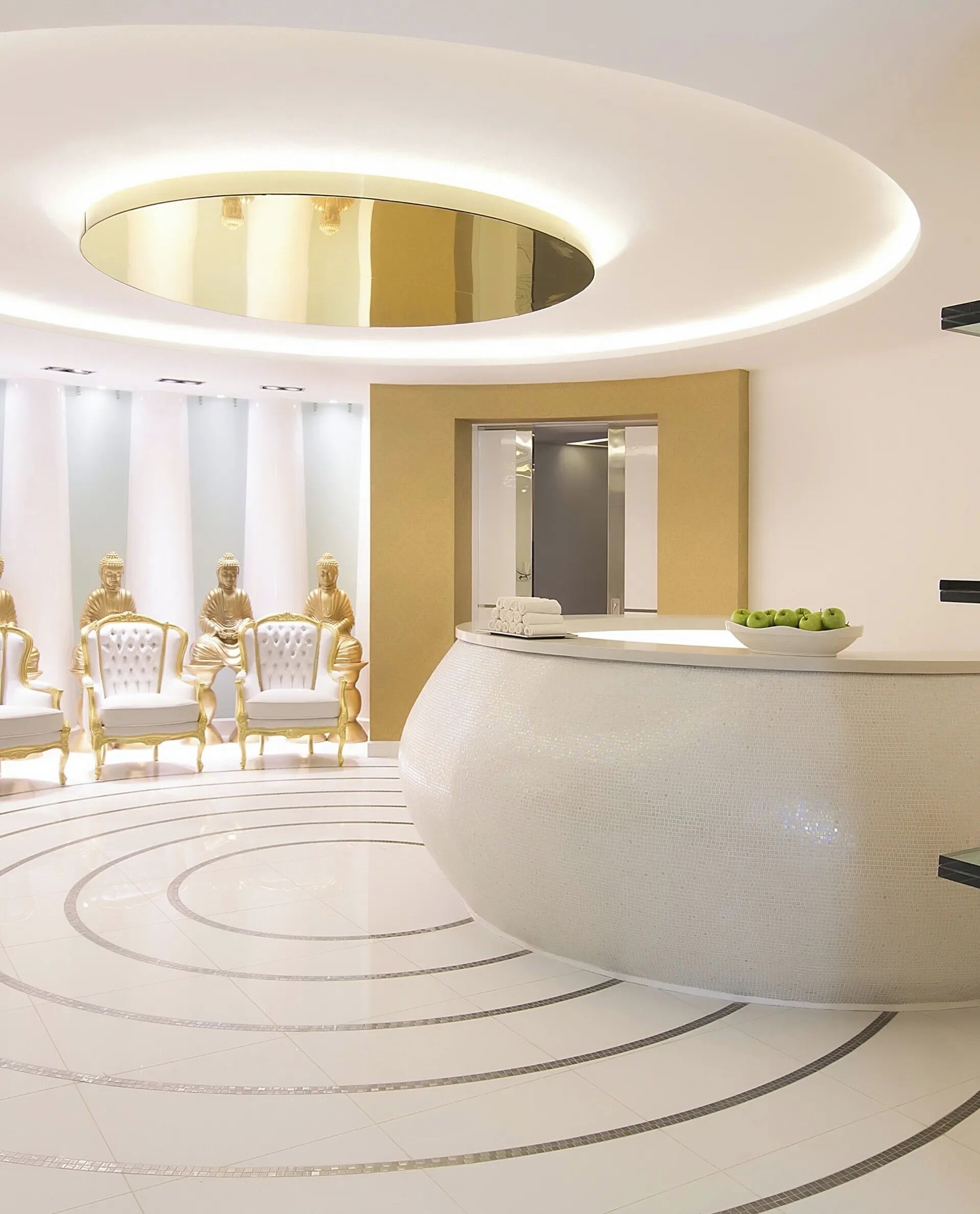A modern reception area with a circular design, a large mirror, and golden statues.