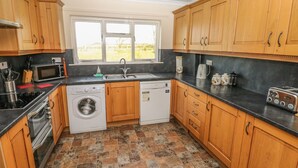 Une cuisine avec des meubles de rangement en bois, un lave-linge, un lave-vaisselle, un four à micro-ondes et un grille-pain.