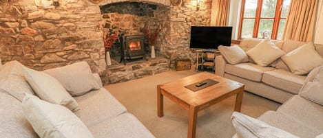 A cozy living room with a stone fireplace, a television, and comfortable seating.