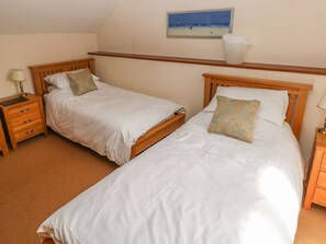 A bedroom with two single beds, wooden headboards, a nightstand with a lamp, a shelf above the beds, and a framed picture on the wall. - Maerdy Lodge (Haverfordwest)