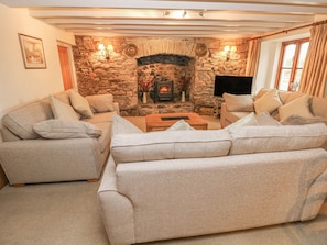 Una sala de estar con chimenea de piedra, dos sofás, una mesa de centro y un televisor.