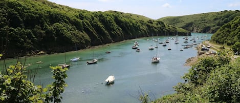 A river with boats, surrounded by green hills.