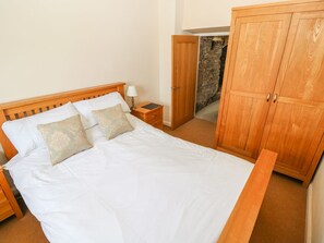 Un dormitorio con cama de madera, mesita de noche y armario.