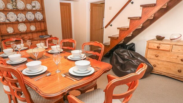 Un coin repas avec une table en bois dressée pour six personnes, entourée de chaises assorties.