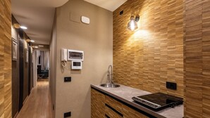 A modern kitchen with a built-in stove, a sink, and a wooden backsplash. - HELMIRAGE Frattina Suite (Rome)