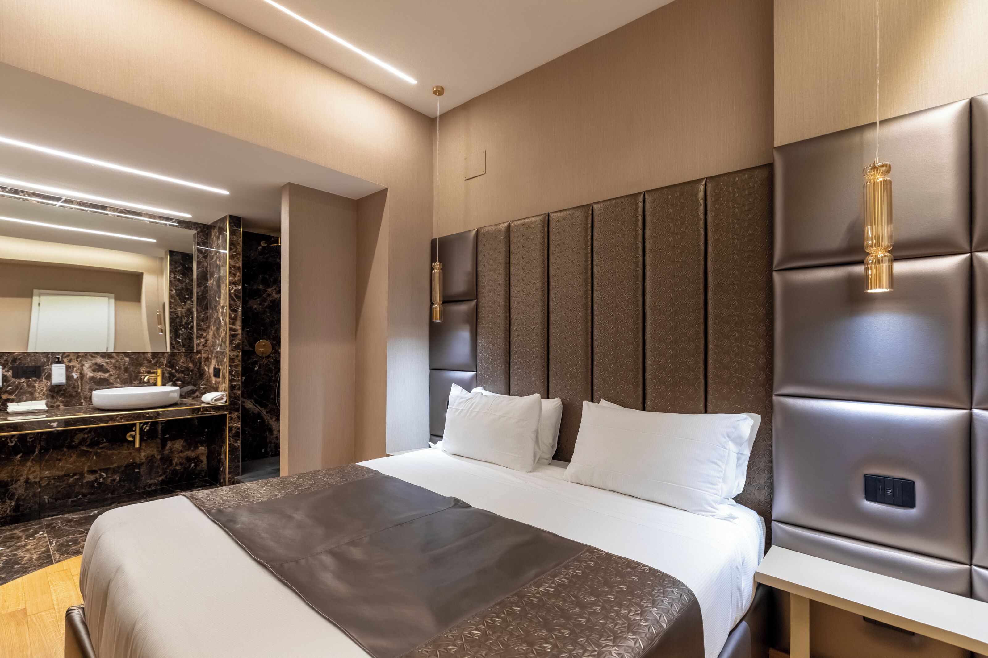 Une chambre d’hôtel moderne dotée d’un grand lit, d’une coiffeuse intégrée avec un miroir et d’une tête de lit au design original.