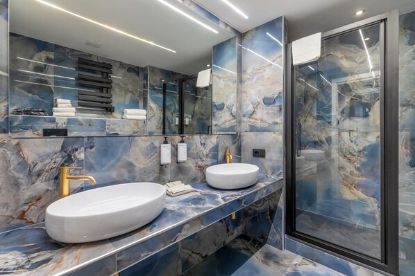 A modern bathroom with two sinks, a large mirror, and a glass shower enclosure.