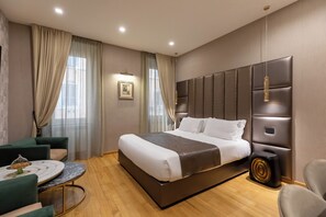 A modern hotel room with a large bed, a round table, and a seating area.