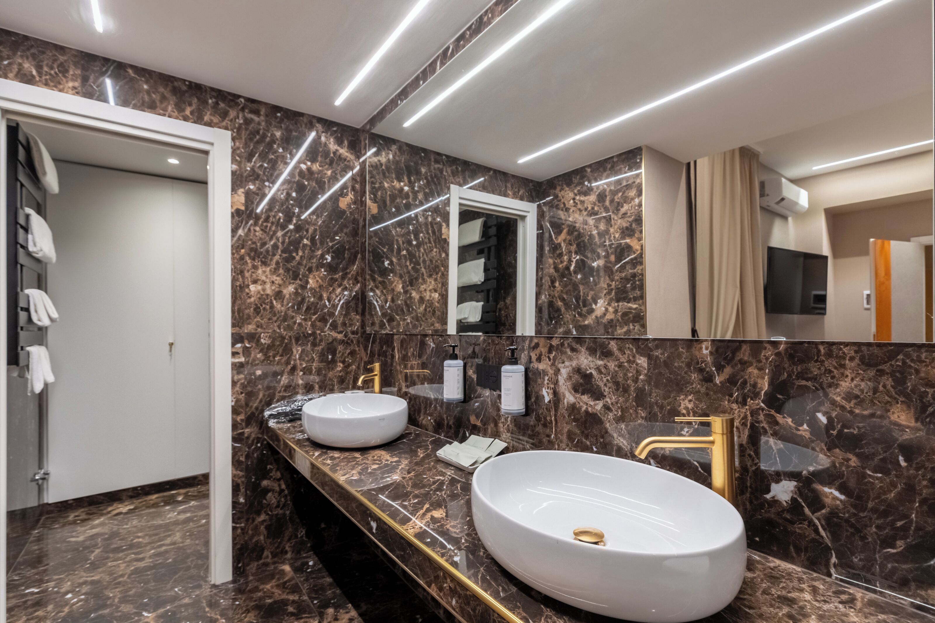 A modern bathroom with two sinks, marble walls, and a large mirror.