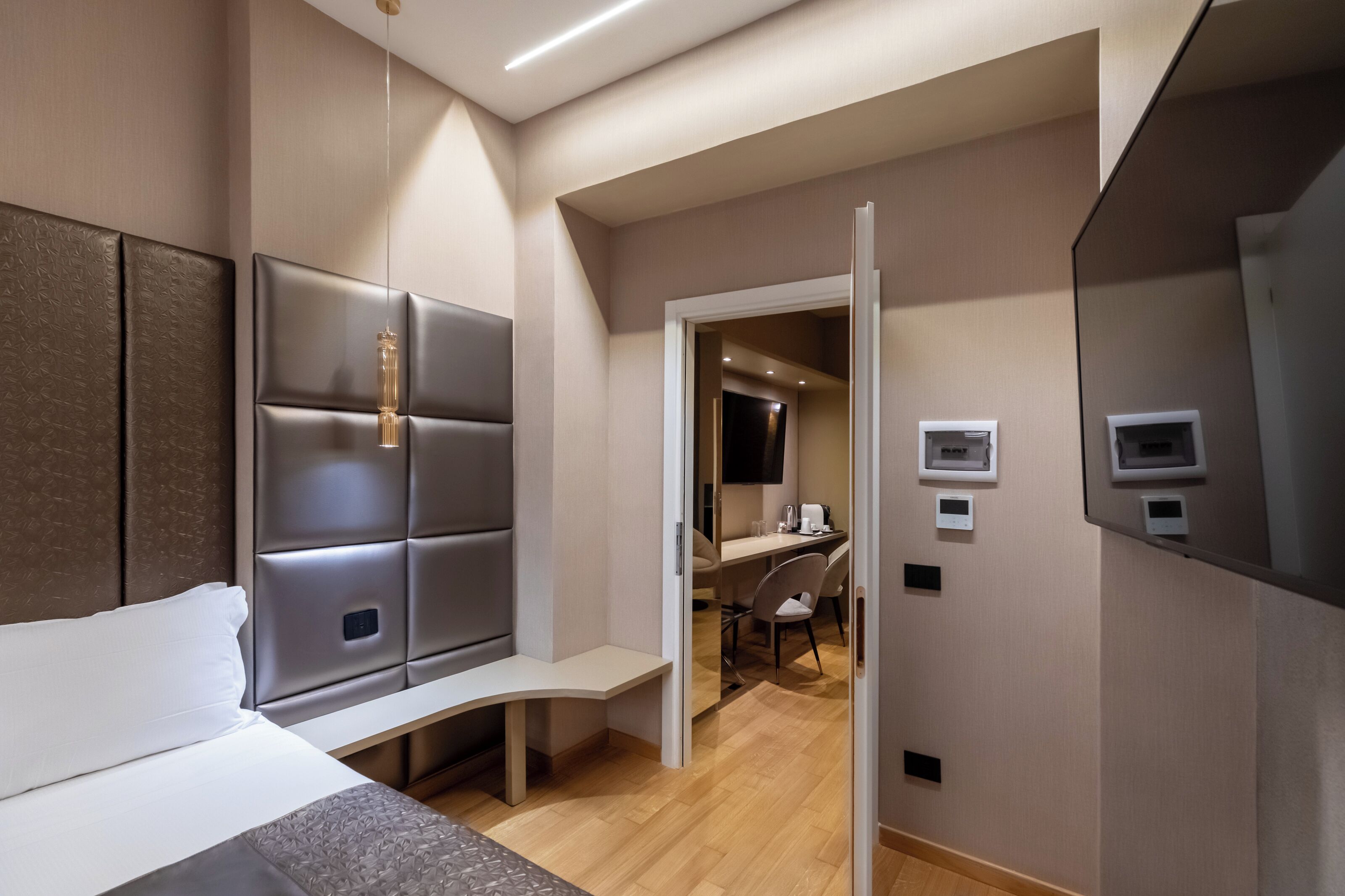 Une chambre d’hôtel moderne équipée d’un lit, d’un coin salon, d’un bureau et d’une télévision.