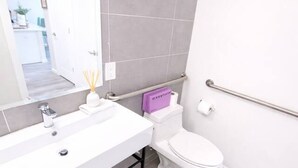 Moderni kylpyhuone, jossa on valkoinen pesuallas, wc-istuin ja peili.