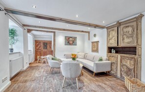 A spacious living room with a sofa, two armchairs, a wooden floor, a large cabinet, and a dining area with chairs and a table. - Munkler Mühle Whg: 1 (Irrhausen)