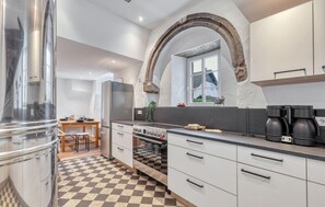 A kitchen with a checkered floor, a refrigerator, a stove, and a window with a view. - Munkler Mühle Whg: 1 (Irrhausen)