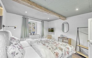 A bedroom with a bed, a chair, a TV, a mirror, and a window with curtains. - Cozy apartment in Irrhausen with WiFi (Irrhausen)