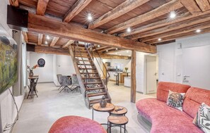 Ein großzügiger Wohnbereich mit einer Holztreppe, einem roten Sofa und einem Esstisch.