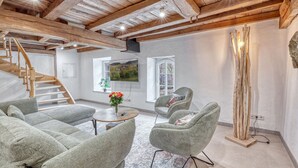 A spacious room with a wooden staircase, a round table with a vase, and two upholstered chairs. - 2 bedroom beautiful apartment in Irrhausen (Irrhausen)