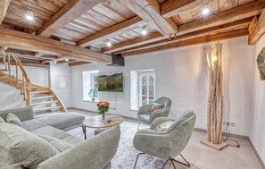 A spacious room with a wooden staircase, a round table with a vase, and two upholstered chairs. - 2 bedroom beautiful apartment in Irrhausen (Irrhausen)