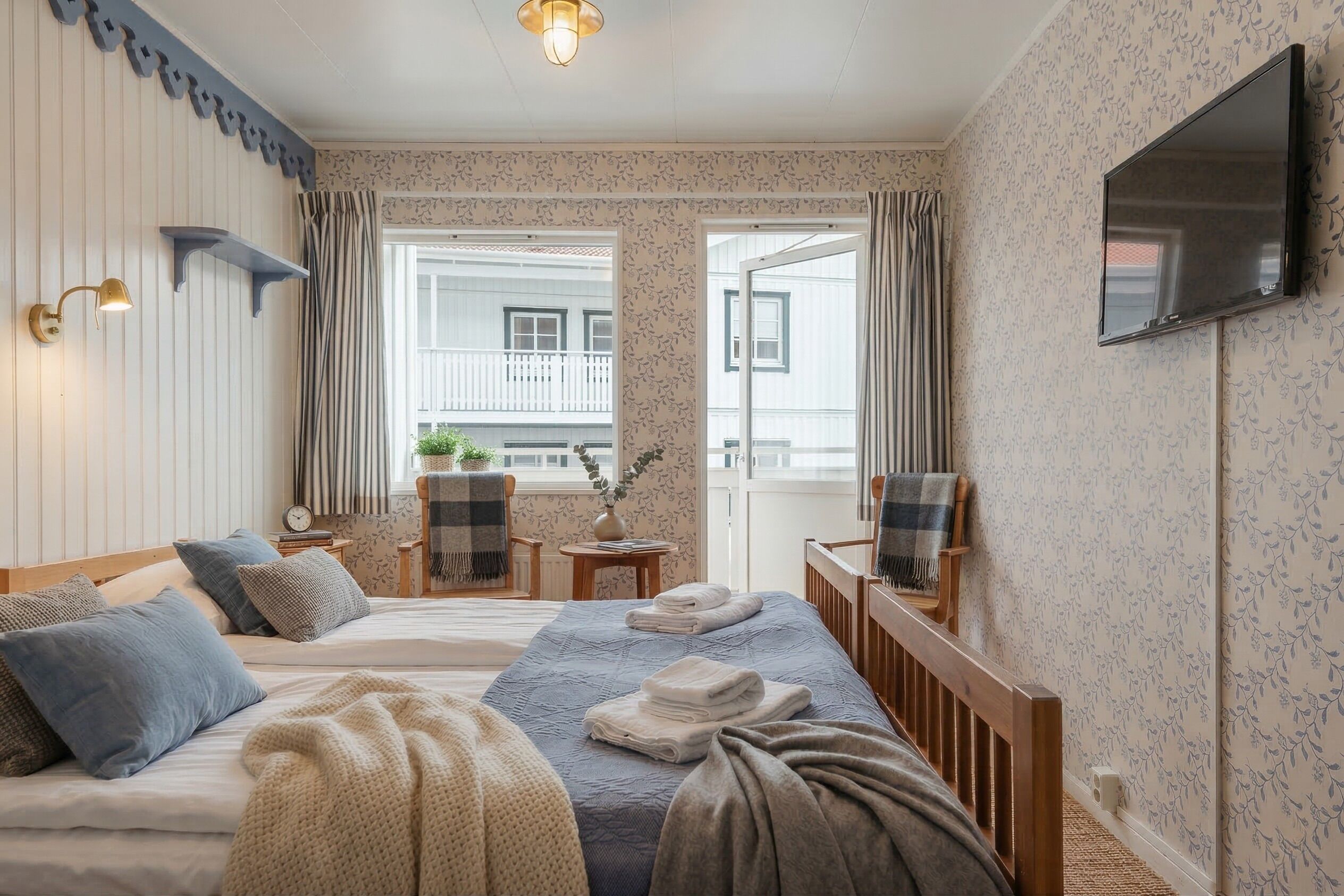Ett hotellrum med en säng, en TV, ett fönster och en balkong.