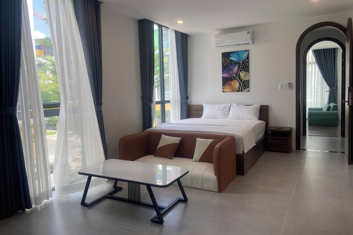 Ein modernes Hotelzimmer mit einem Bett, einem Sofa, einem Tisch und Blick ins Freie.