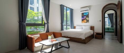 Una habitación de hotel moderna con cama, sofá y una mesita con una revista y botellas de agua.