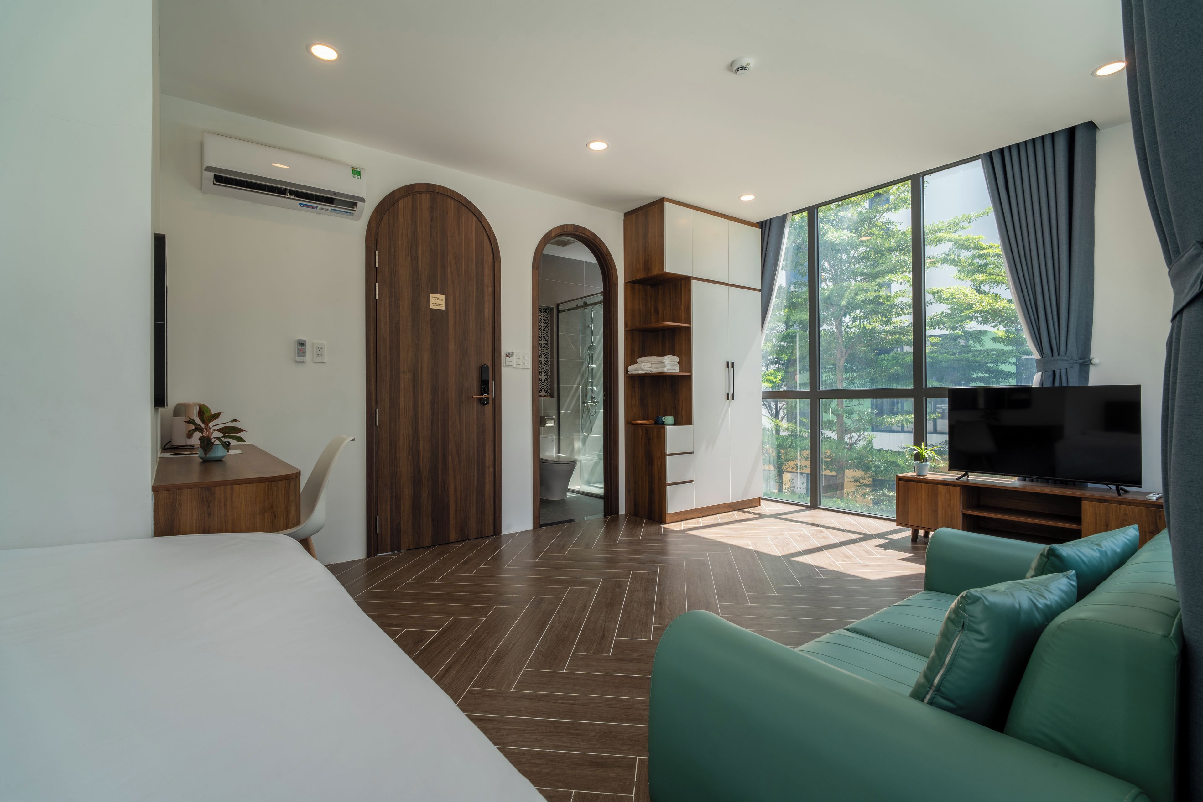 Una habitación de hotel moderna con una cama grande, televisión, sofá y vistas al exterior.