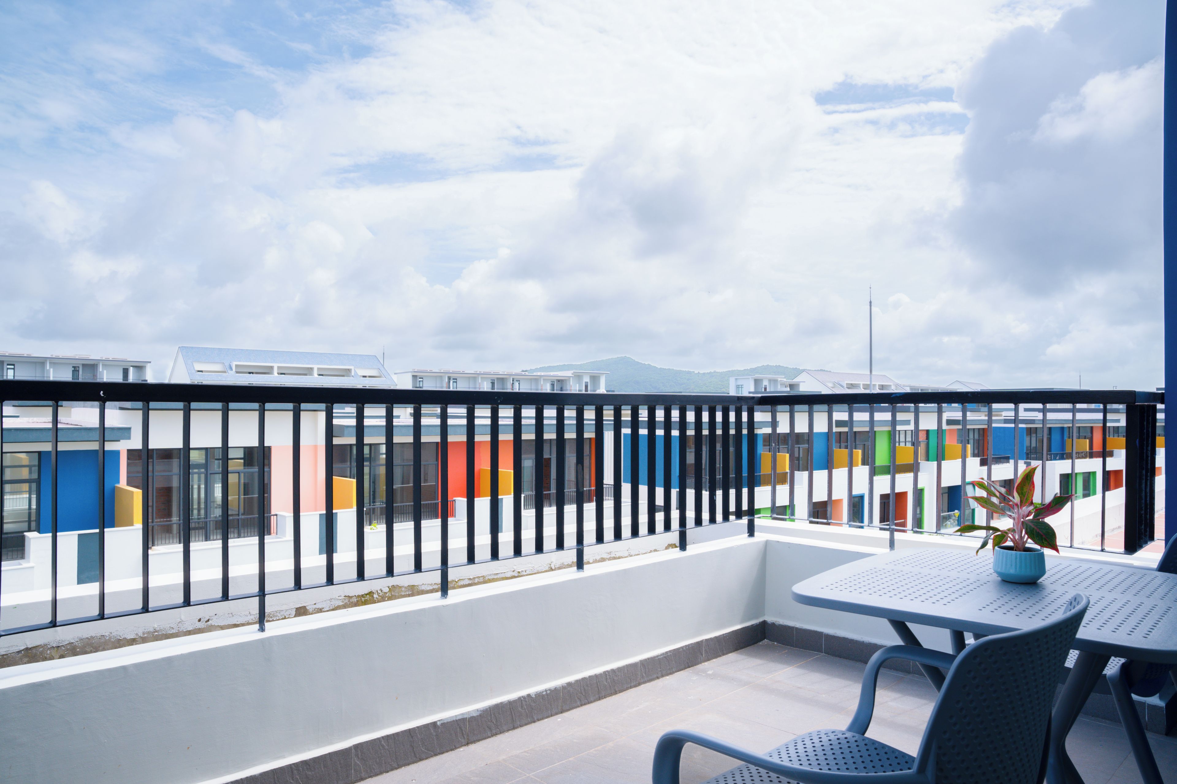 A balcony with a metal railing, a table, and chairs.
