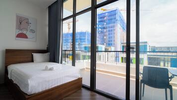 Habitación de hotel con una cama grande, vista a una obra en construcción y un balcón con una silla.