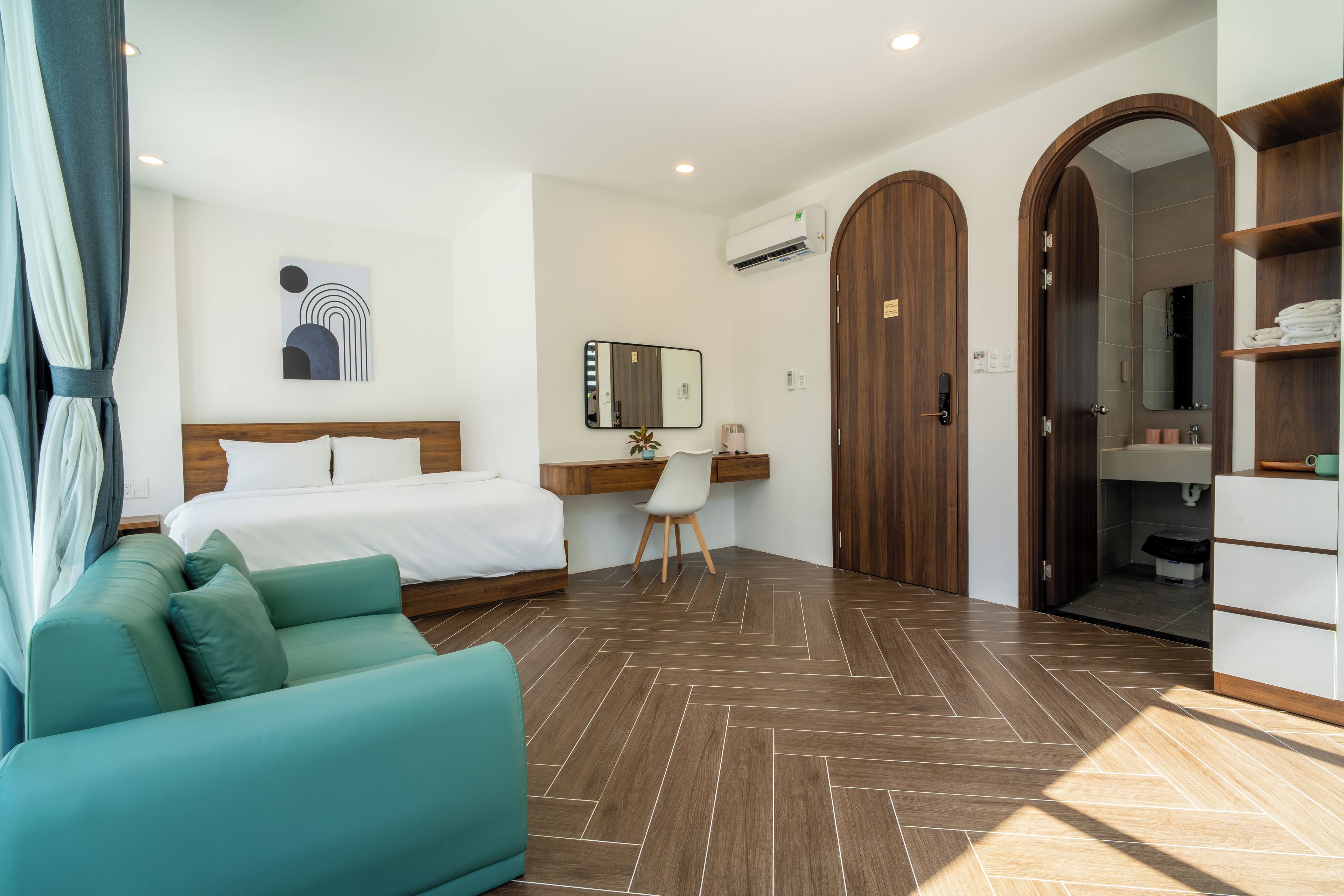 A hotel room with a bed, a desk, a chair, a wardrobe, and a bathroom.