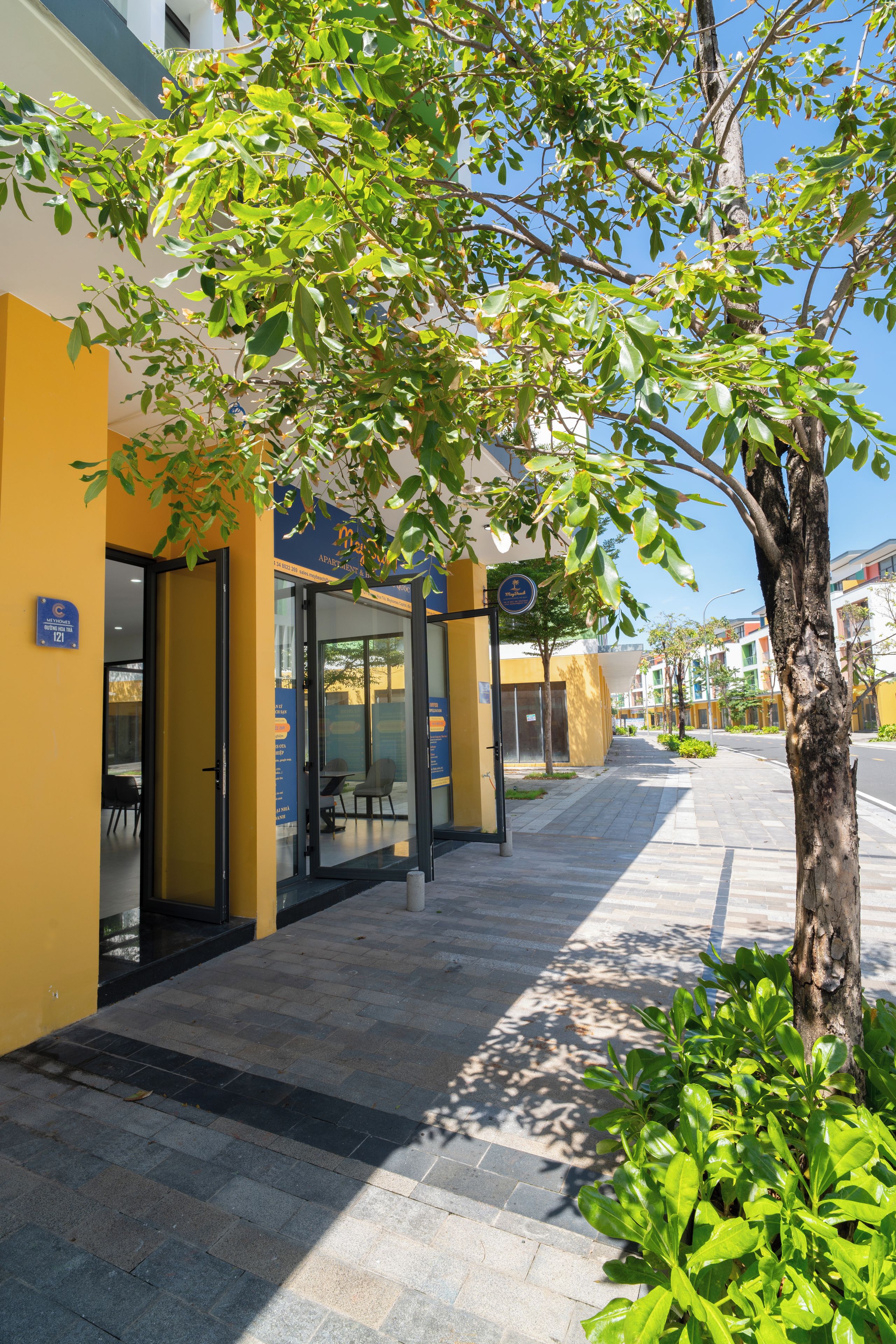 A building with a yellow facade, a glass entrance, and a clear sky.