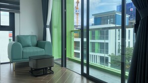 A modern room with a teal sofa, a small table, and a large window offering a view of a building with scaffolding.