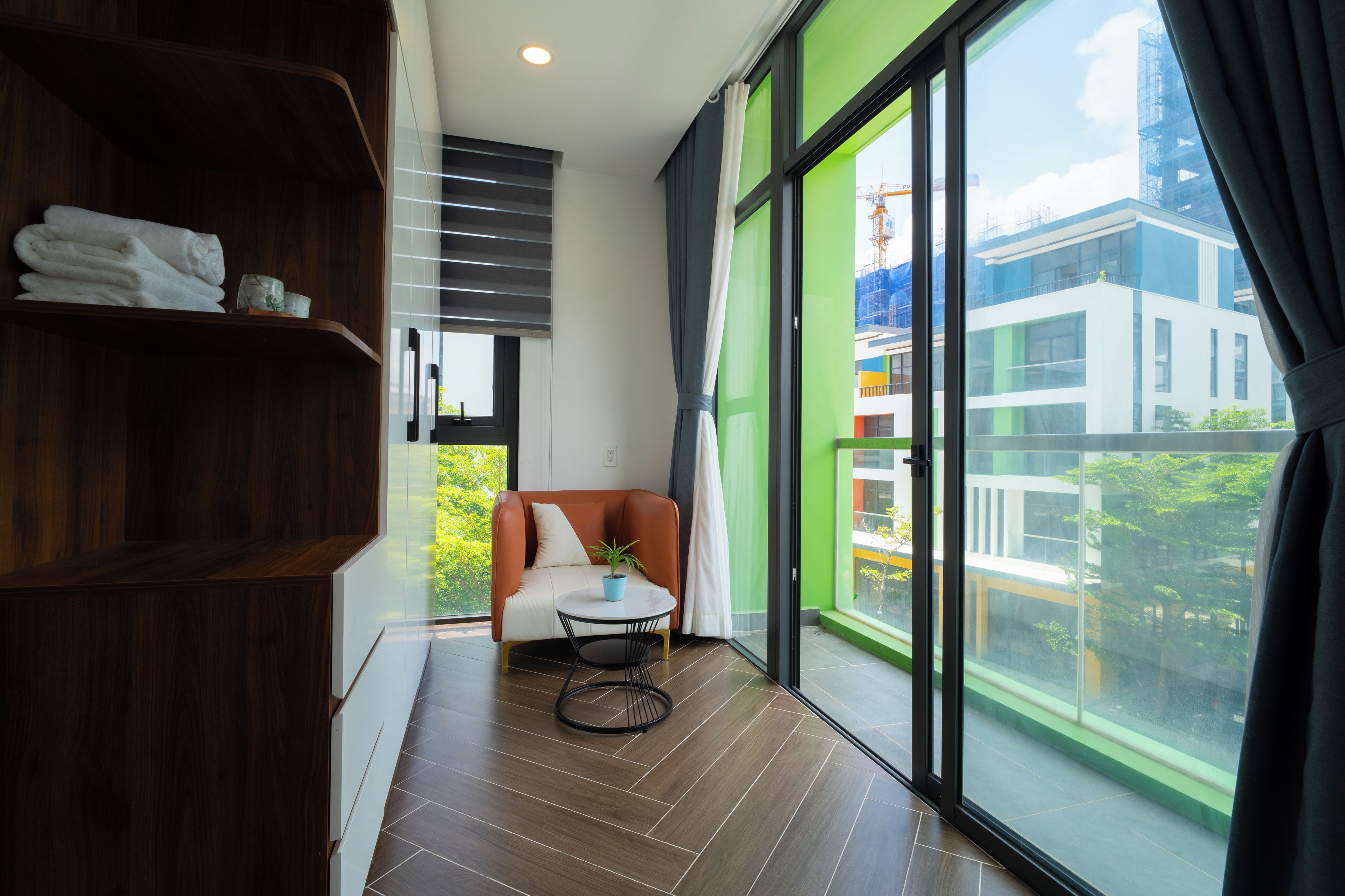 Una habitación moderna con un ventanal grande, un sofá, una mesita y una estantería.