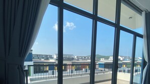 A hotel room with a large window, a bed, and a view of the airport.