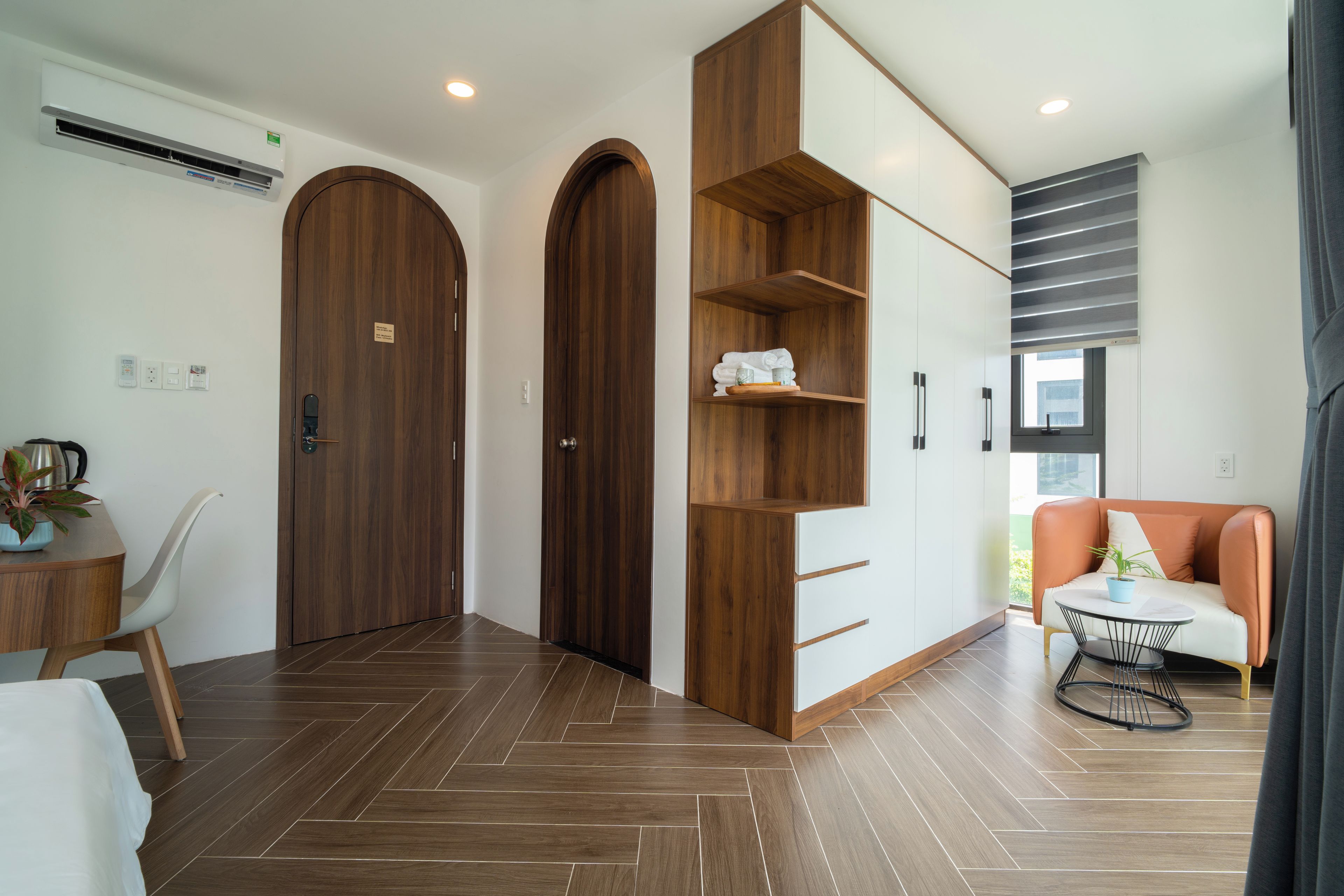 Een moderne hotelkamer met houten vloeren, een bank, een eettafel en ingebouwde kasten.