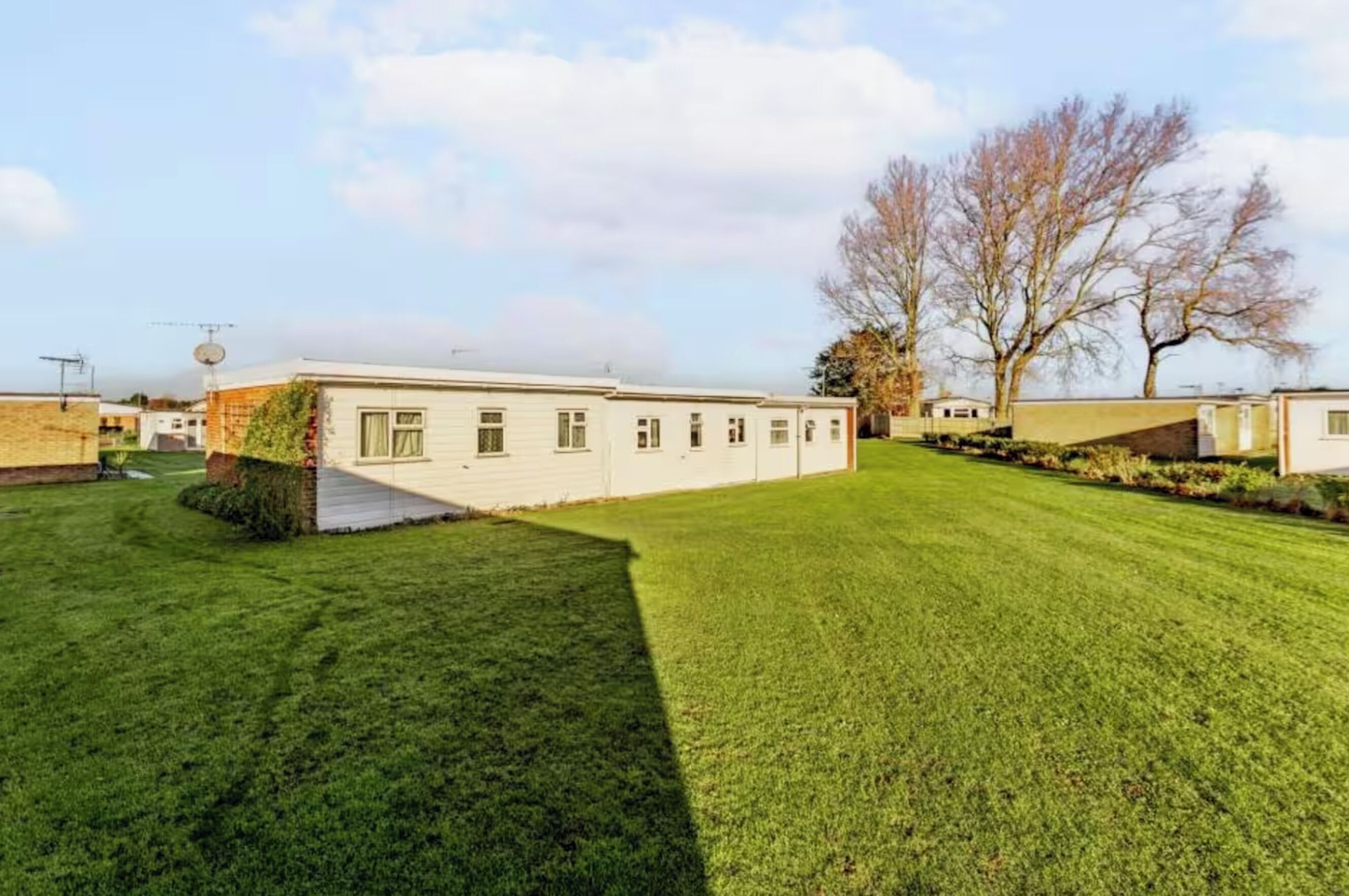 A single-story mobile home with a flat roof, a small front porch, and a well-maintained lawn.